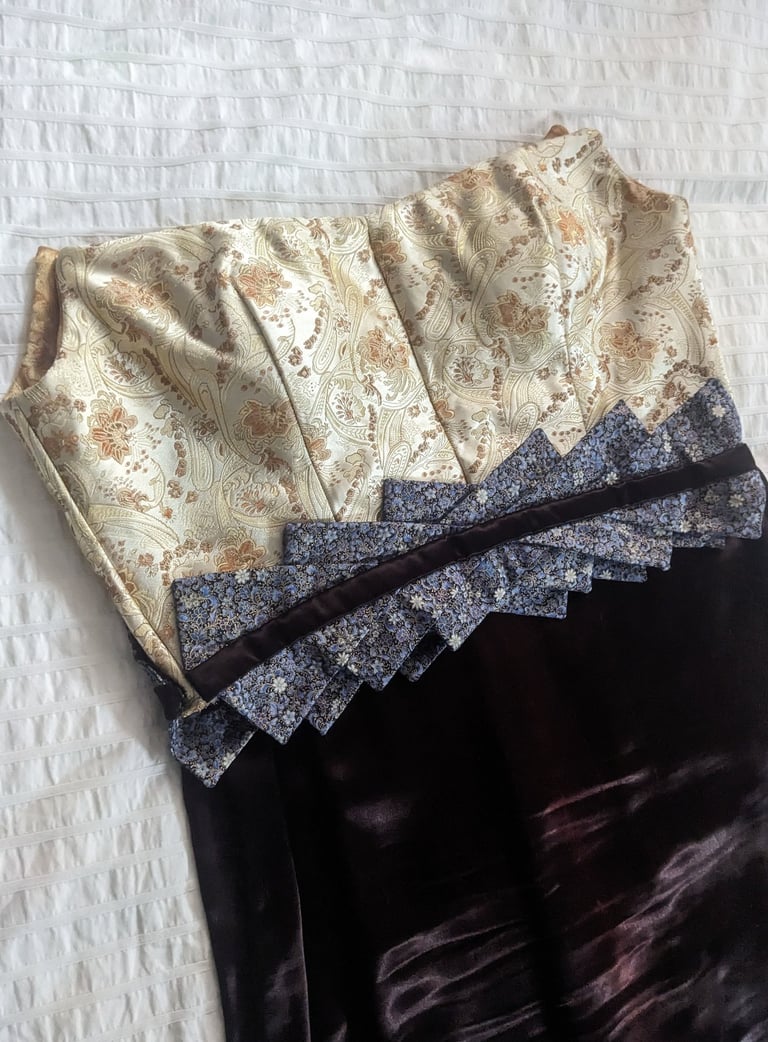 The front of the bodice of a gold brocade and brown satin evening gown