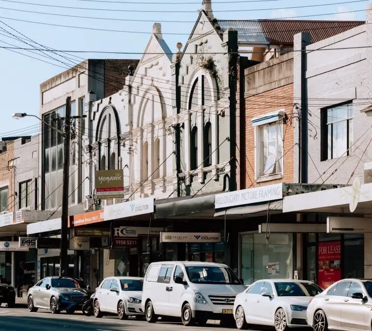Willoughby storefronts and parked cars on a sunny suburban Sydney street in Willoughby.