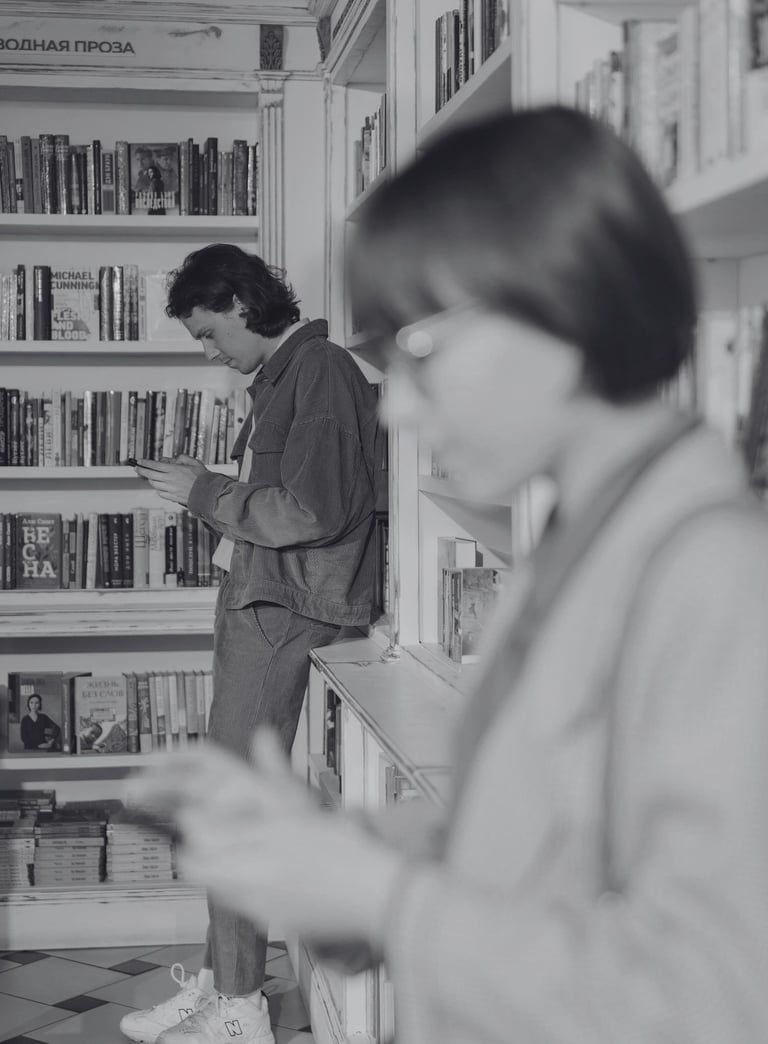 two people check their dating apps while browsing books in a quiet bookshop, showcasing slow dating