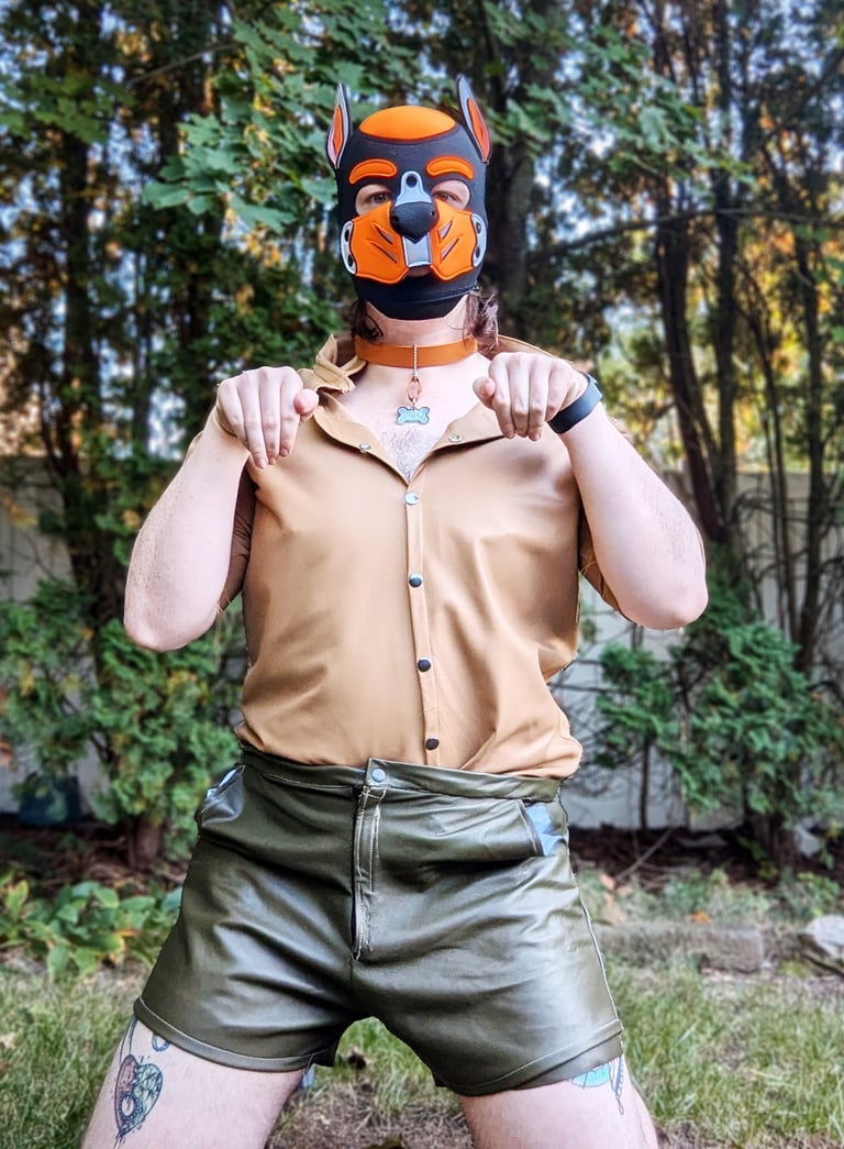 A man posing outdoors in a pup mask.