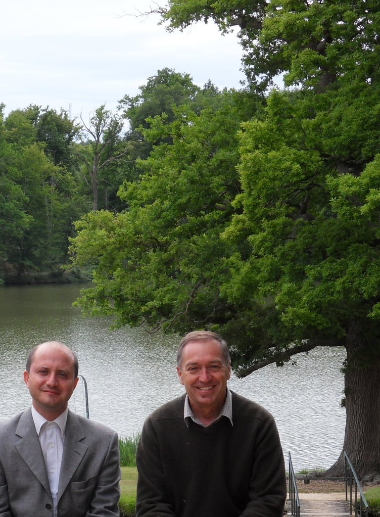 Maitre Pistone et Maître Gestat de Garambé devant lac et paysage arboré.
