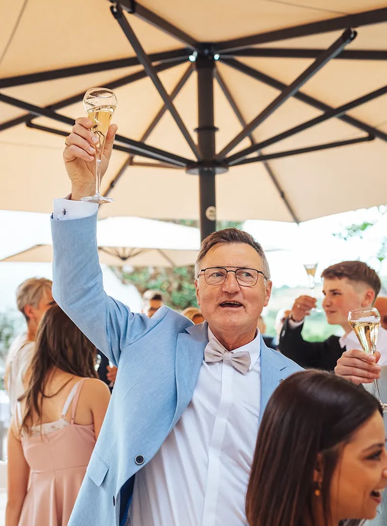 Homme qui lève son verre durant le vin d'honneur d'un mariage.