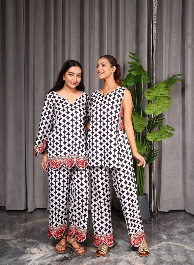 two women standing next to each other in matching patterned outfits
