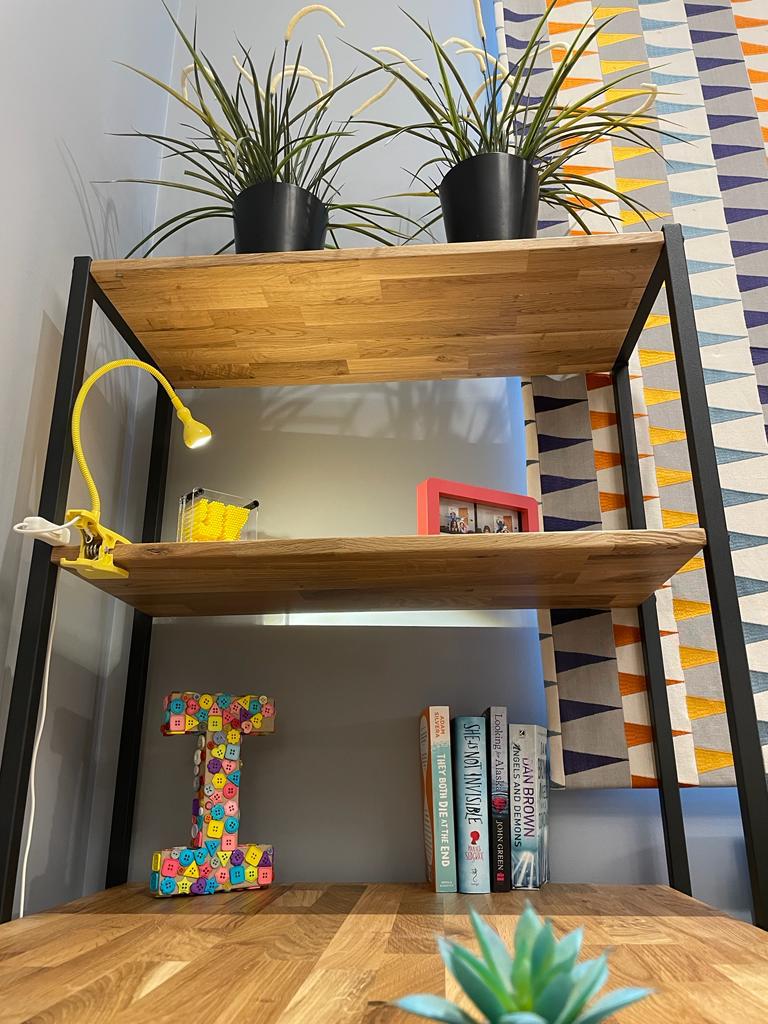 tall storage beside study table with clip on study lamp, accessories and plants