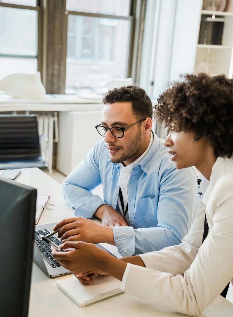 a man and woman sitting at a desk with a laptop