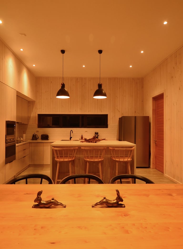 Una cocina con una mesa y sillas y una cocina., luz suspendida en mesa