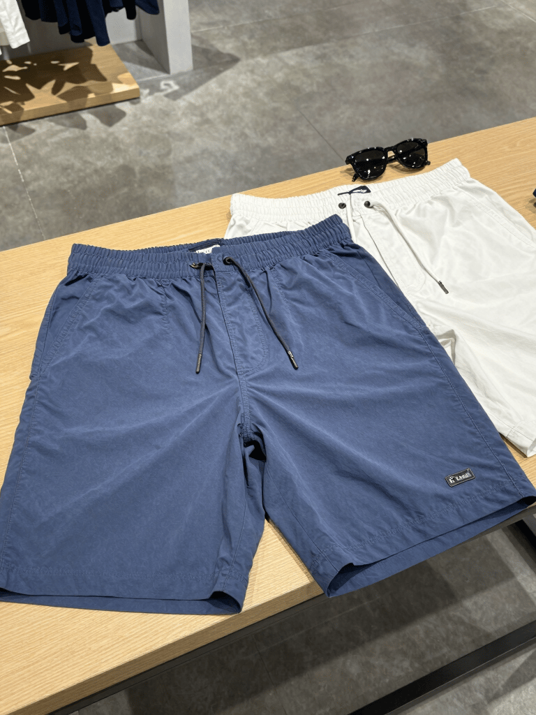 A stylish pair of capris displayed on a wooden bench with sunlight filtering through leaves.