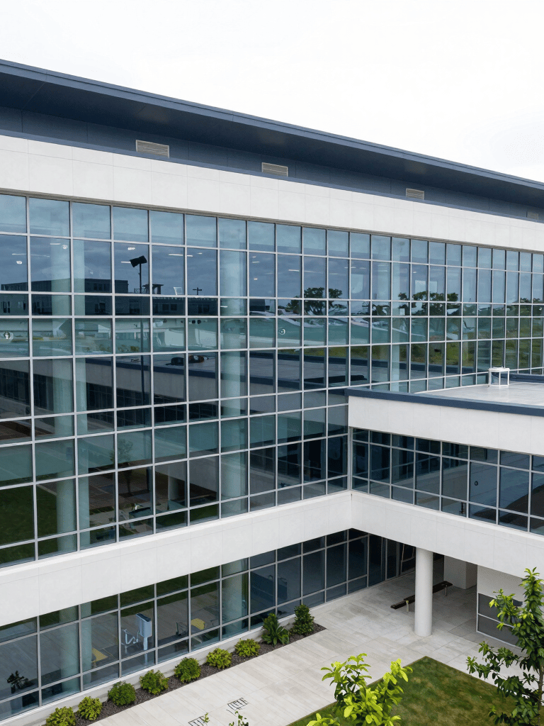 A high-angle professional photograph of a modern North American medical facility with glass walls and dark blue accents, bright natural lighting, and a clean minimalist aesthetic.