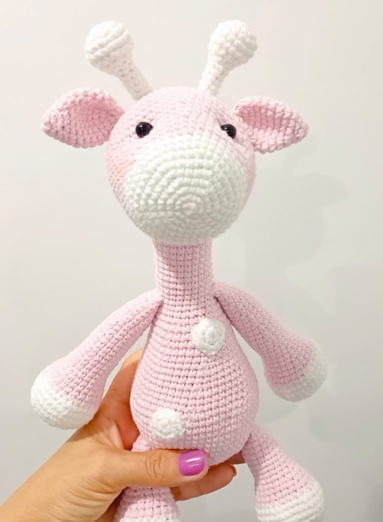 Handmade pink and white amigurumi giraffe crochet plush toy for nursery decor.