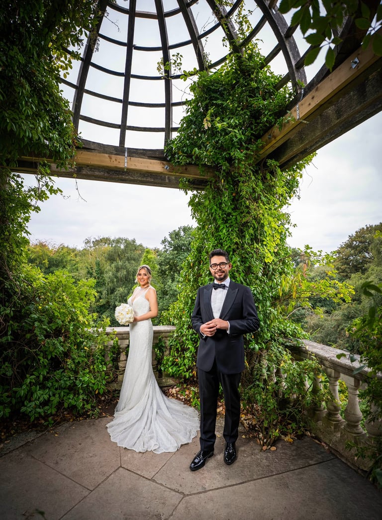 Bride and groom posing under a vine-covered pavilion, captured by Fred Art Studio