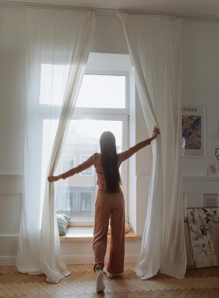 Women opening the day curtains letting the light into the room