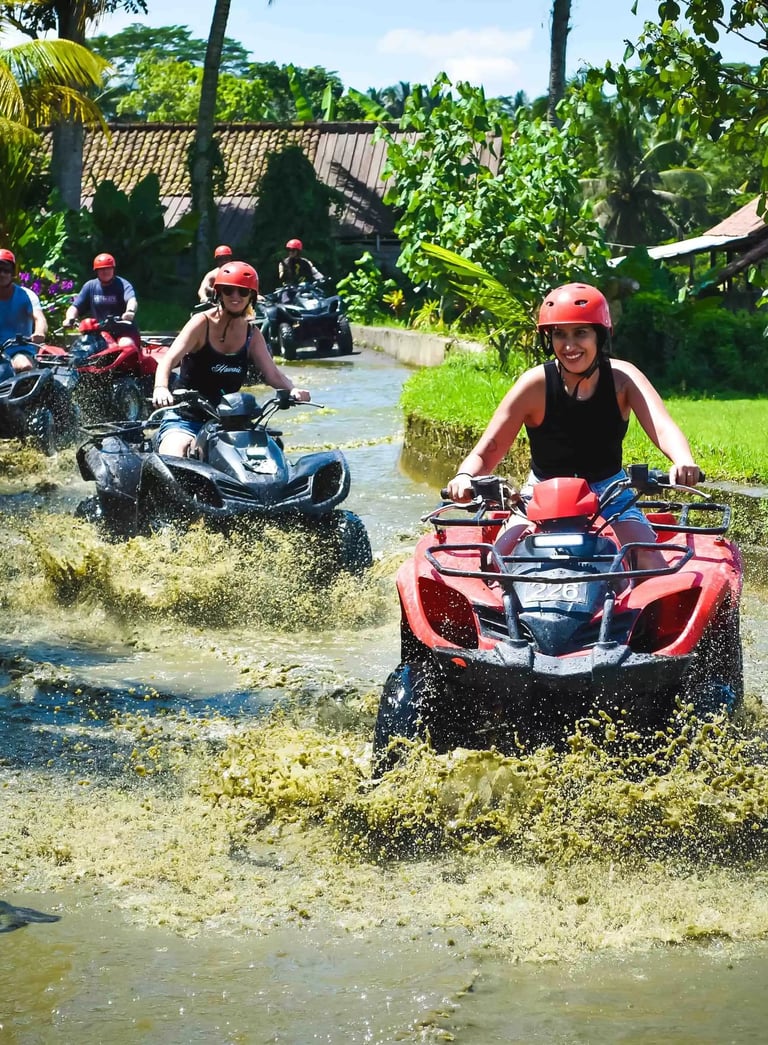 Group of tourists riding quad bikes through muddy water on a Bali ATV jungle tour.