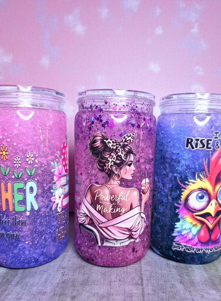 Three custom glitter snow globe tumblers with teacher, empowerment, and rooster designs.