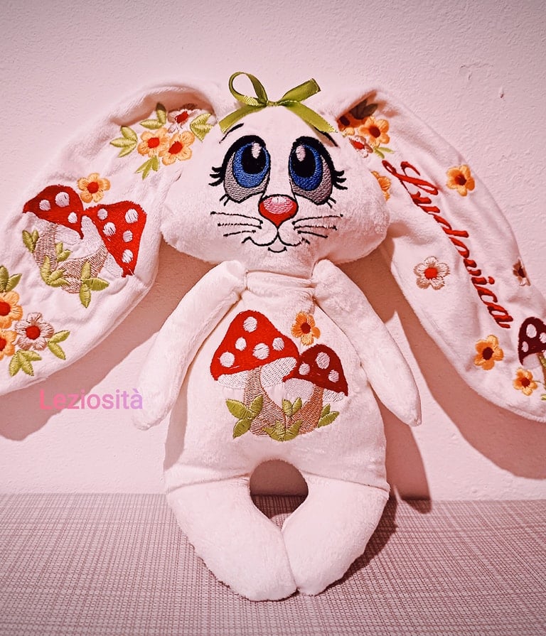 Customized white plush bunny with floral embroidery and red mushrooms on ears and belly.