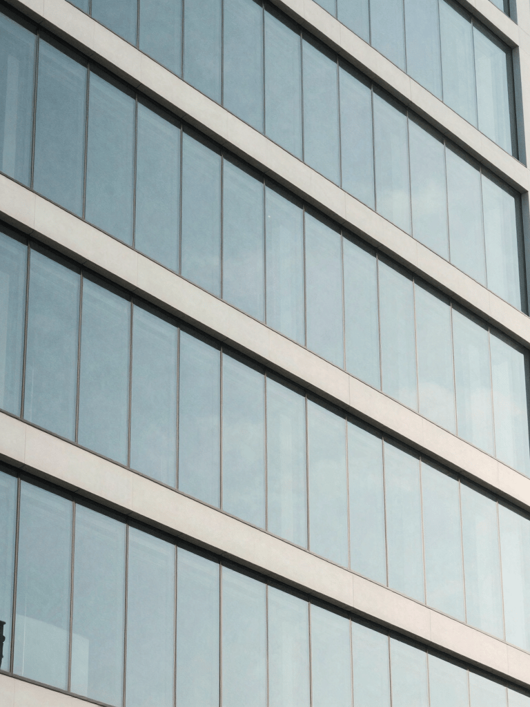 A sleek, minimalist photography of a modern Italian business building glass facade, reflecting a clear sky, symbolizing transparency and efficiency, white and pale blue tones.