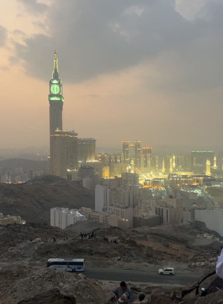 Makkah Royal Clock Tower and Great Mosque of Mecca at sunset from a rocky overlook.