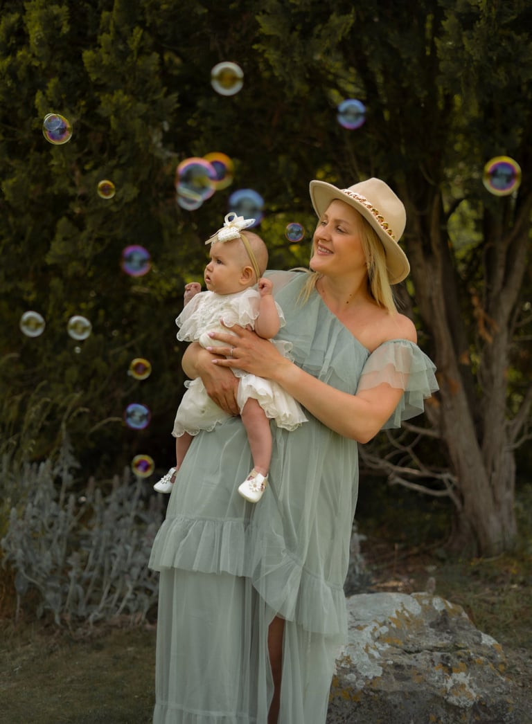 Woman with hat holding her baby playing with bubbles