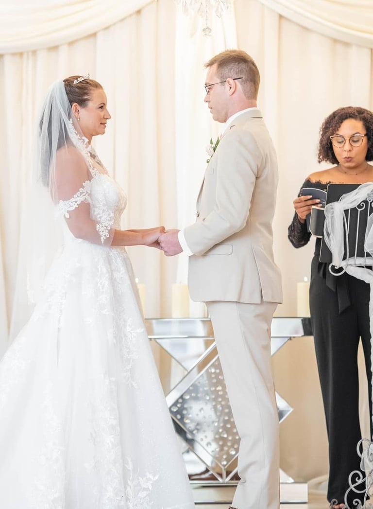 Bride and groom exchange wedding vows during an elegant indoor ceremony with a female officiant.