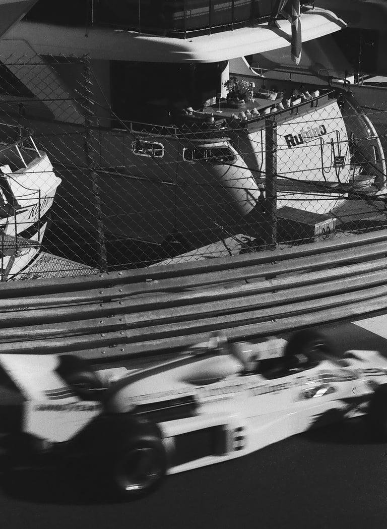 a race car racing down the track with a boat in the background in Monaco
