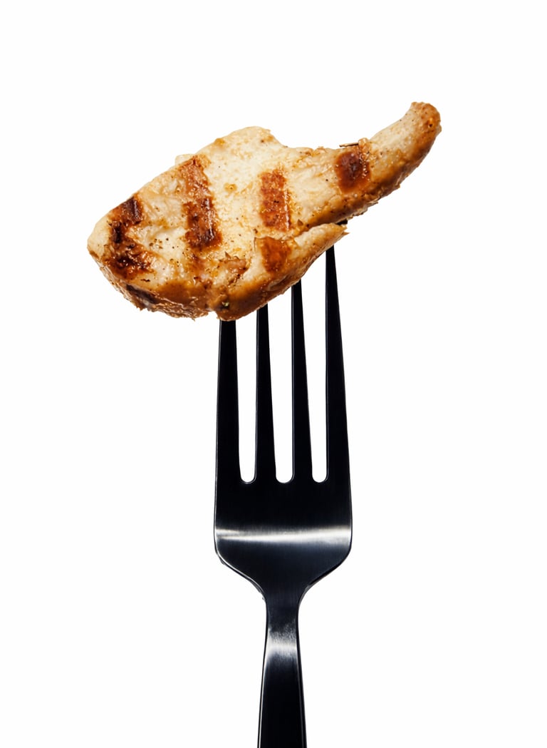 A single piece of grilled chicken breast with char marks on a metal fork, isolated on white.