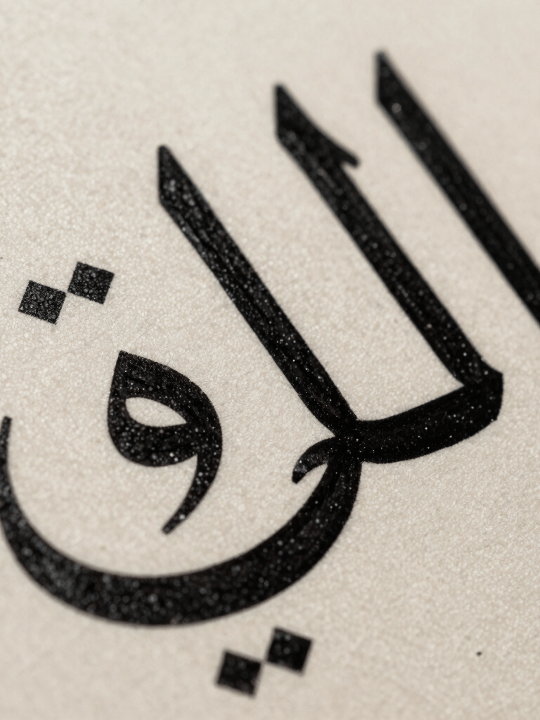 A macro photograph showing the rich texture of paint on a canvas by Khaled Tirikli. The subject is a section of an Arabic letter in deep black ink, with subtle charcoal grey highlights, emphasizing the high-end artisan craft of the piece.