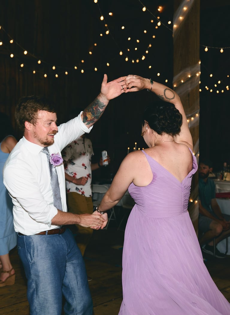 a man and woman in a purple dress dancing at a wedding reception