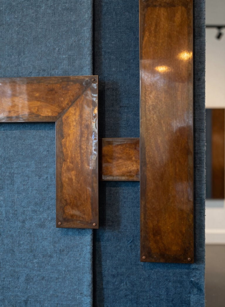 Photography of a mixed-media art installation in a Northern European / Welsh / British creative hub. The piece features raw Slate Blue textiles interwoven with polished Warm Ochre metal elements, reflecting a sophisticated and innovative approach to traditional craftsmanship in a contemporary setting.