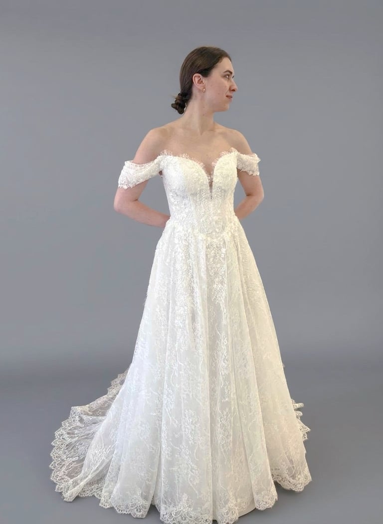 a woman in a white wedding dress with a lace overlayed off the shoulder