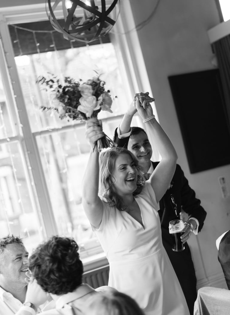 bride and groom raising their hands and smiling 