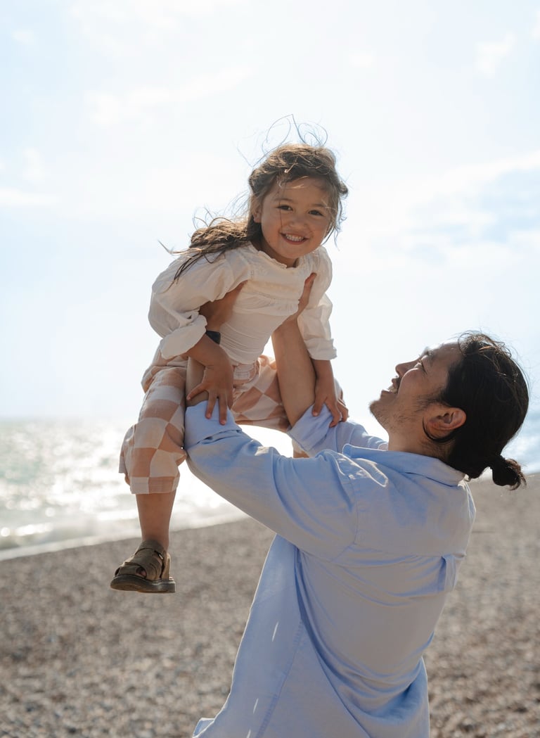 father holding her daughter up in the sky and girl is smiling