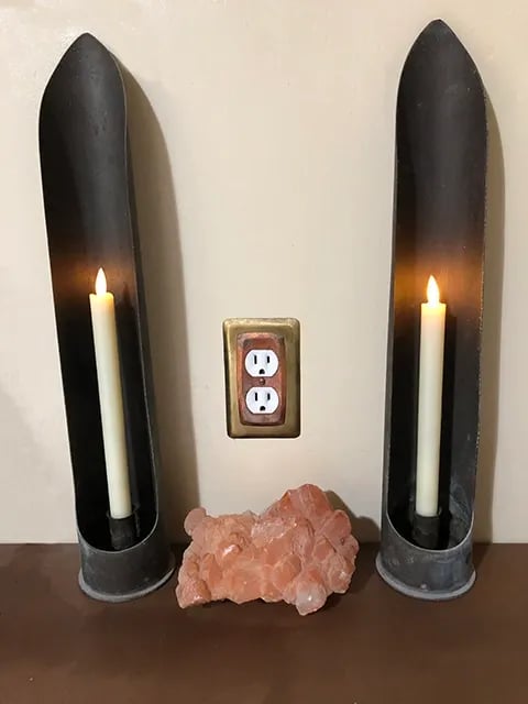 Two artillery shells cut to hold candlesticks with a crystal between them.