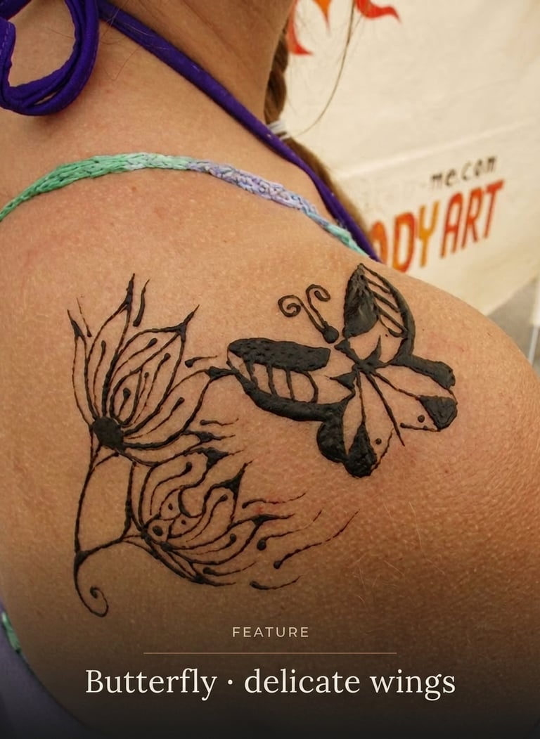 A delicate black butterfly and floral henna tattoo design applied to a woman's shoulder.