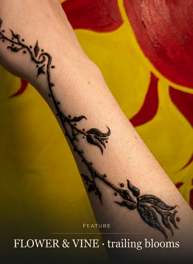 Elegant black henna tattoo featuring a floral vine and trailing blooms on a forearm.