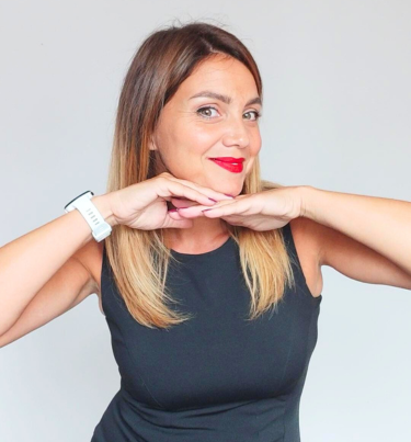 Formatrice en italien souriante, posant le menton sur ses mains, illustrant la page “Qui je suis” et