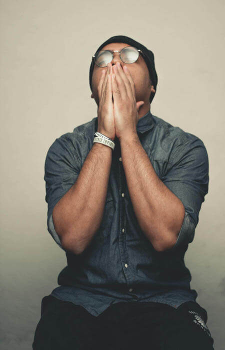 Man sitting with hands covering his face, expressing prayer, struggle, or deep reflection.