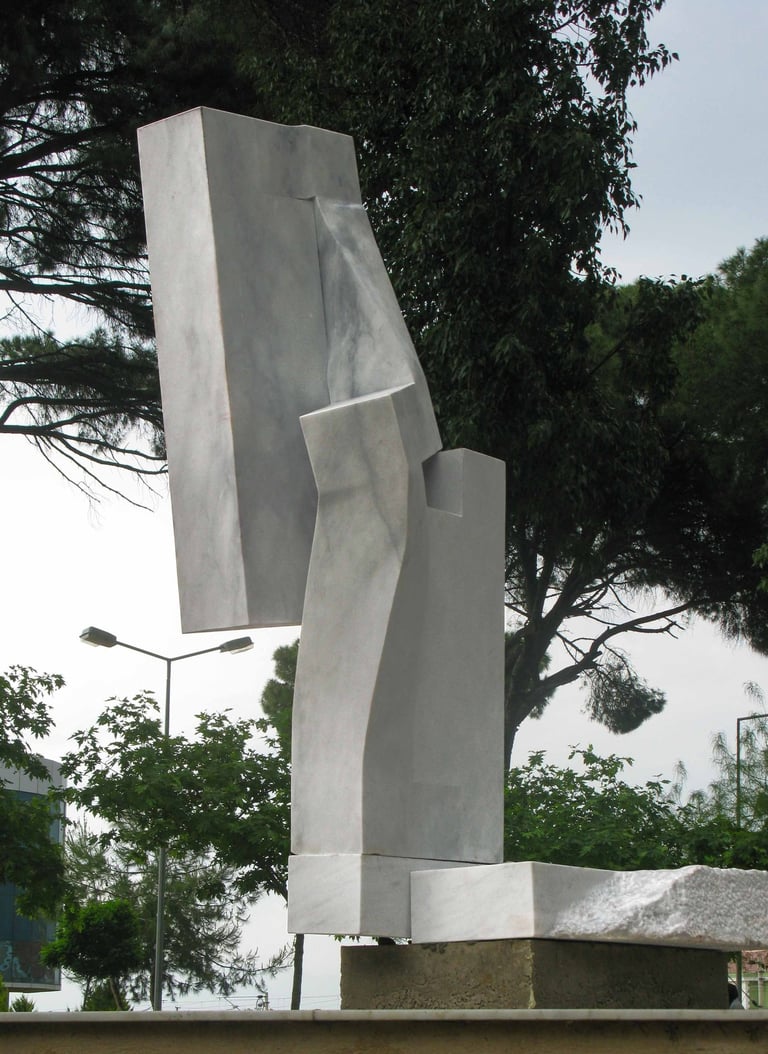 Contemporary abstract marble sculpture with geometric shapes in a public park setting.
