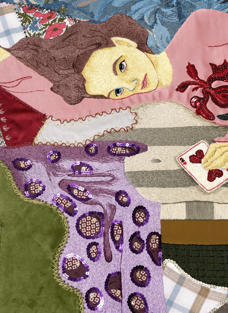 Embroidery details of a woman laying on a couch with a blanket