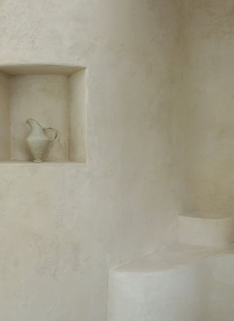 Plastered wall with an architectural niche and a handcrafted pot.