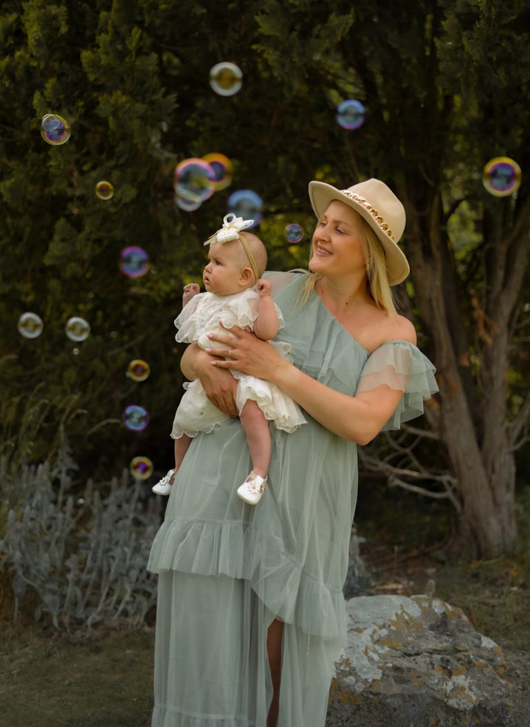 woman holding her baby while playing with bubbles
