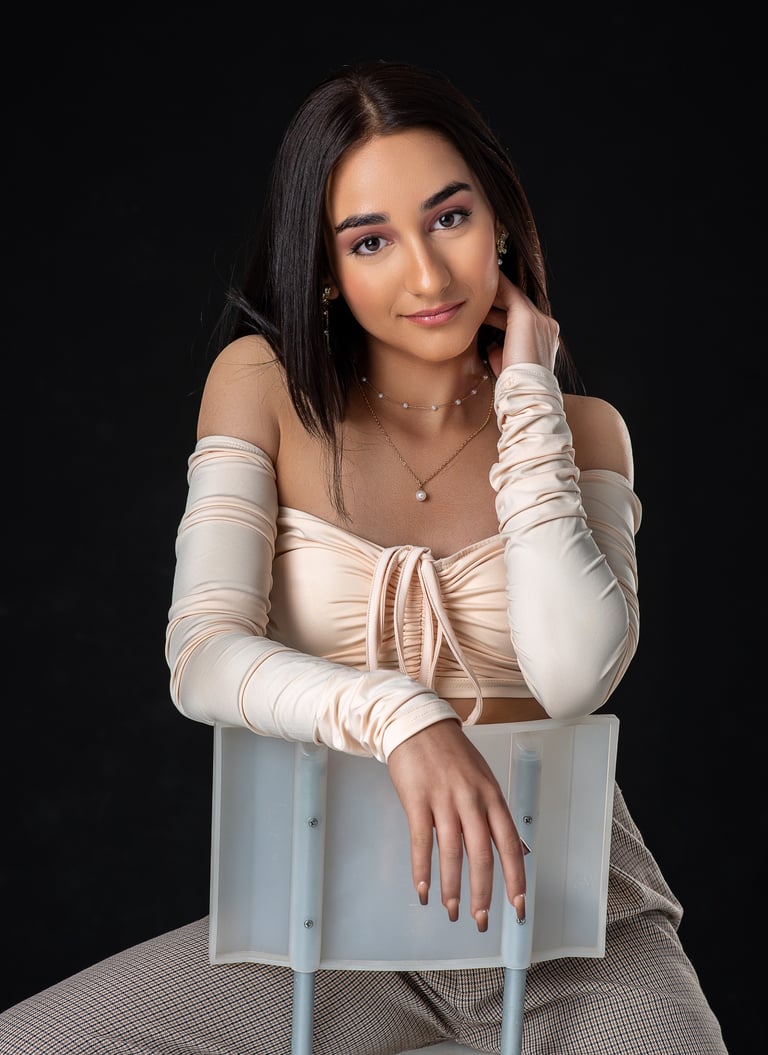 a woman in a beige top and pants sitting on a chair. estudio, quinceañera, retrato, asturias