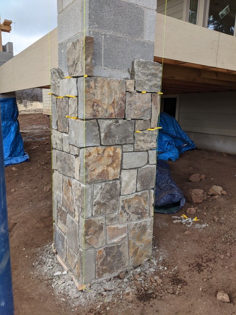 Habillage d’un pilier en blocs de béton avec parement en pierre naturelle