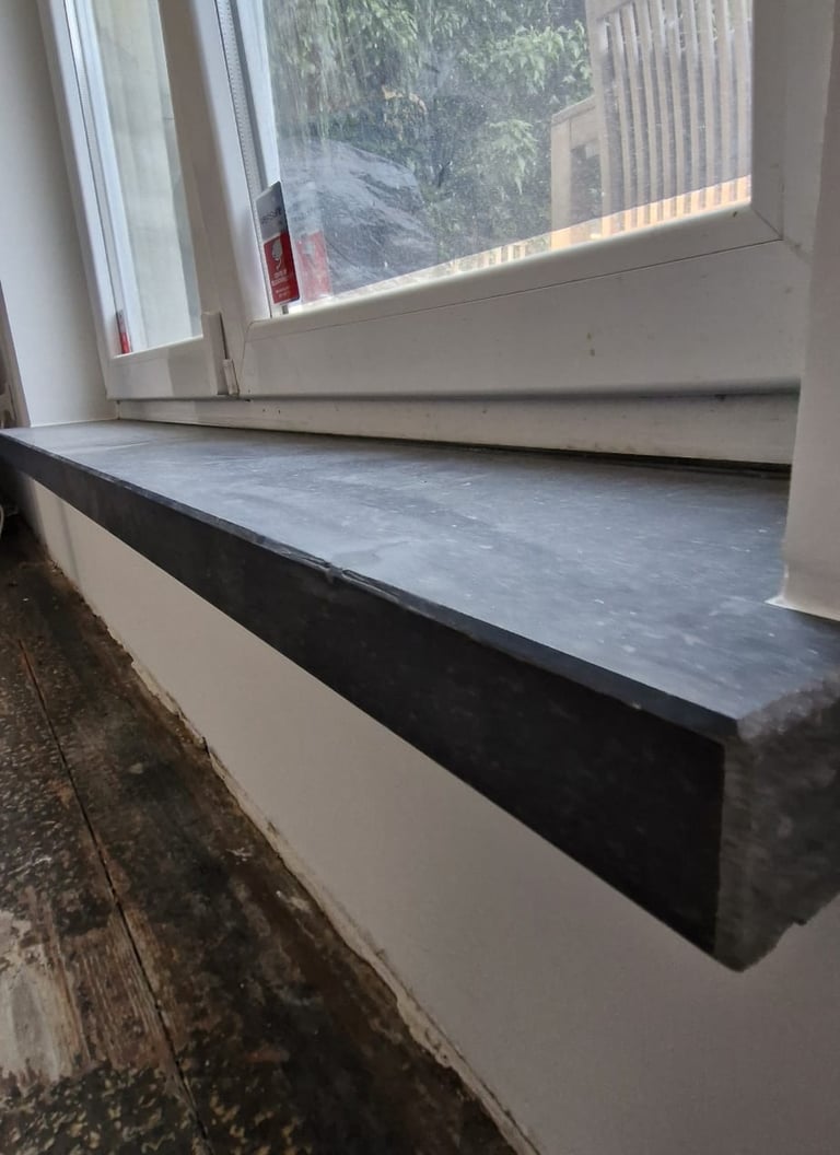 Pose sur mesure d’un appui de fenêtre en pierre bleue dans un logement en rénovation