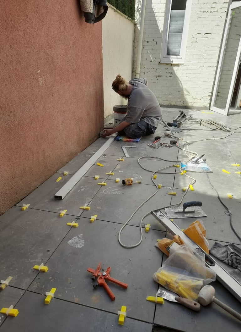 Pose de carrelage extérieur grand format avec croisillons de nivellement dans une cour intérieure