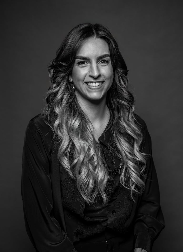 Portrait professionnel en noir et blanc d’une femme souriante aux longs cheveux ondulés portant un c