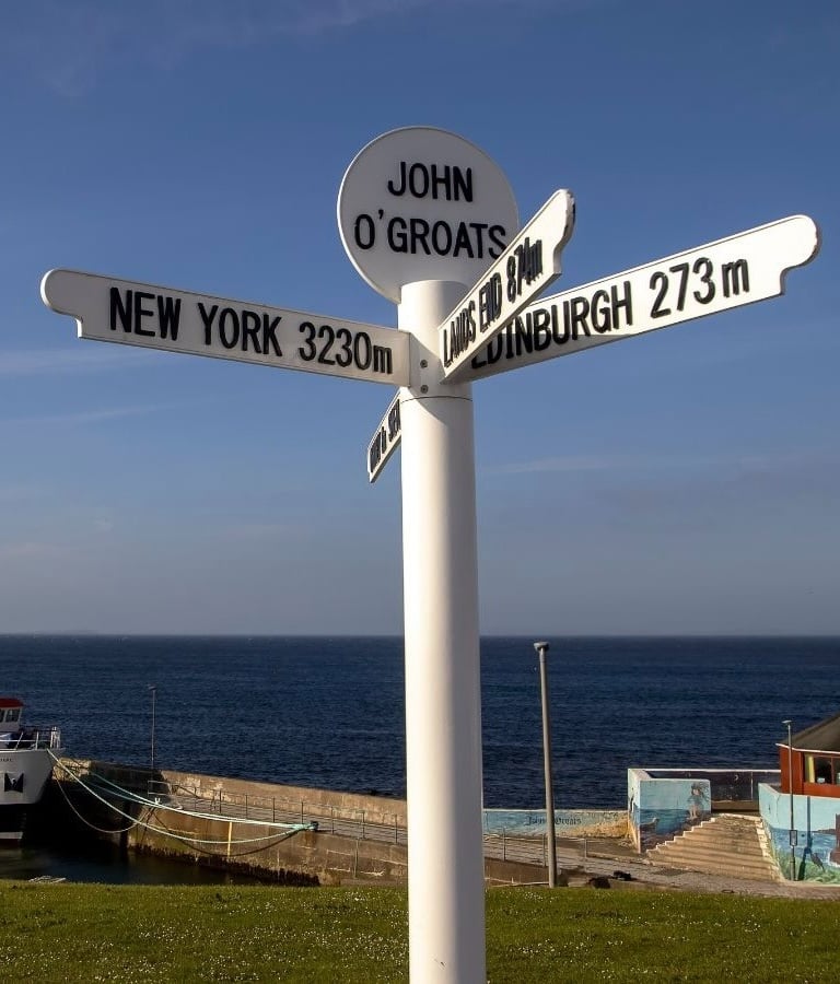 a sign post with a boat in the background