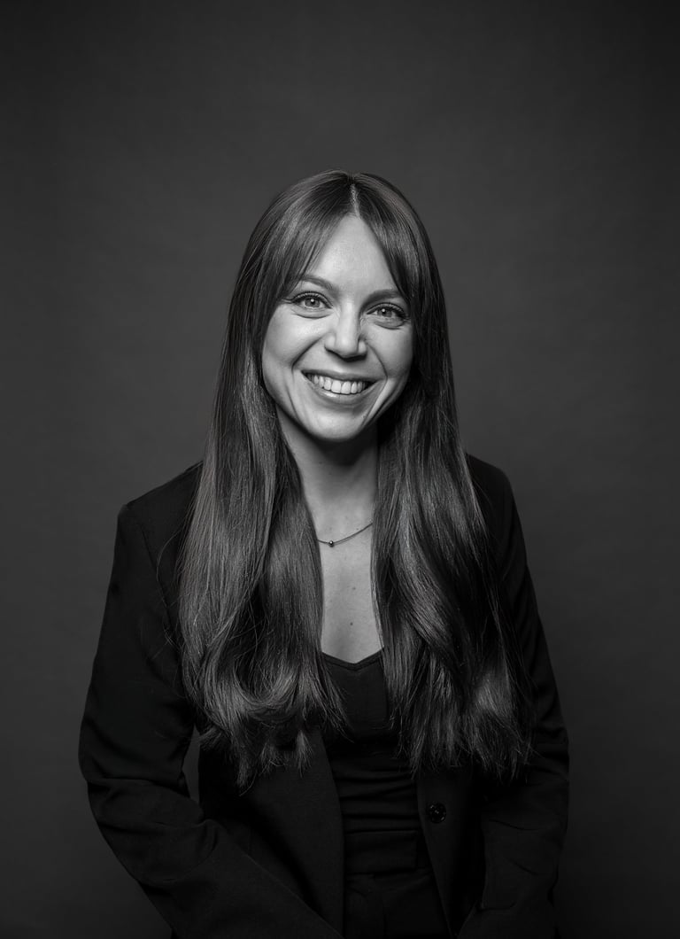Professional black and white headshot of a smiling woman with long hair wearing a blazer.