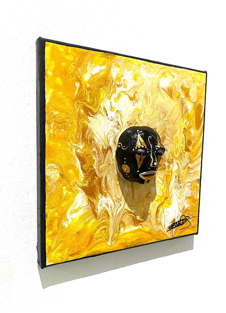 uns sculpture noir ressemblant à un masque qui émerge d'un tableau jaune vu de côtés