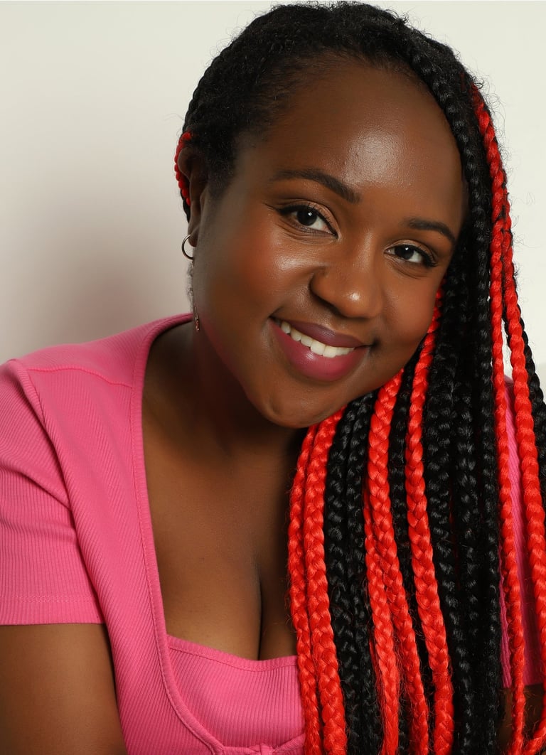a Black woman with a pink top and cardigan, and black and red hair