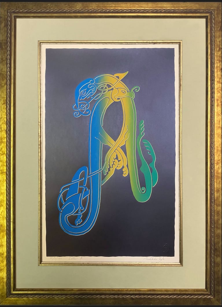 A black handprinted black Irish Celtic letter A in a gold frame 