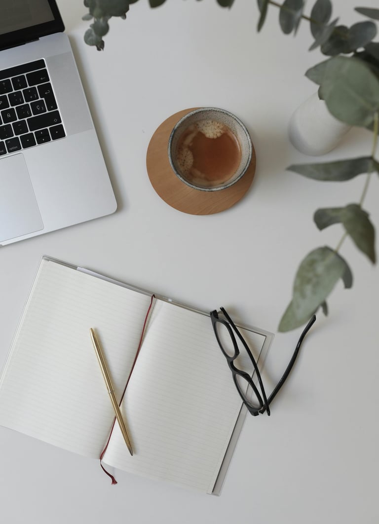 Workspace of a business operations support specialist with a laptop, coffee, and notebook